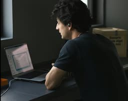 Person working on laptop in dimly lit environment